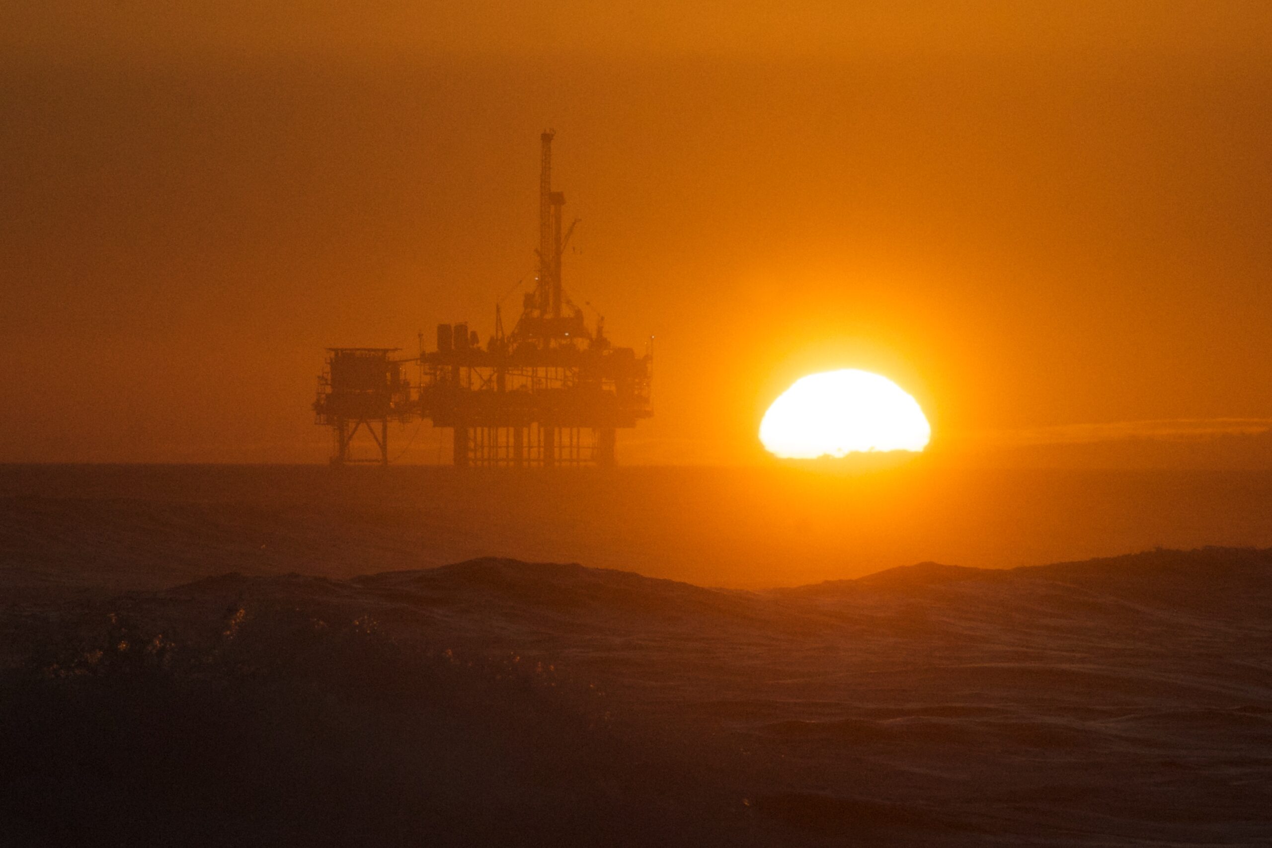 Offshore oil and gas drilling platform against red sky
