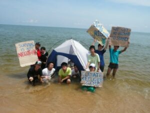 People on beach with banners calling for climate action to prevent rising seas