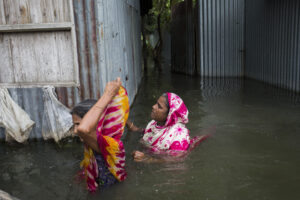Two women leaving flooded house in Bangladesh