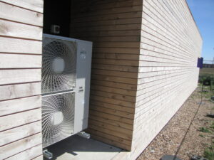 Air source heat pump outside wooden building