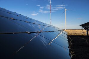 Solar panels and wind turbine in field, an alternative to renewable gas Australia
